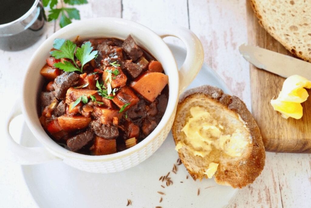 Goulash soup in a bowl with bread and butter.