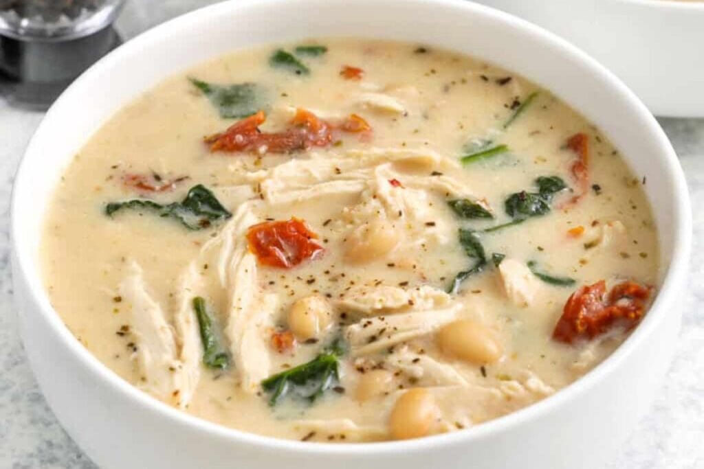Bowl of Tuscan chicken soup with spinach, sun-dried tomatoes, and white beans.