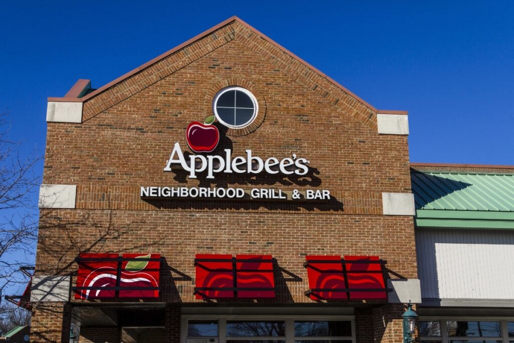 Exterior of Applebee’s restaurant with red logo, brick walls, and green awnings.