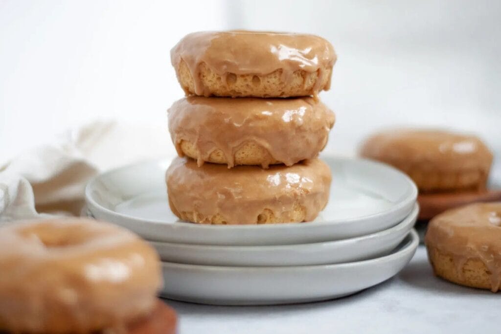 Baked maple donuts stacked on a plate.