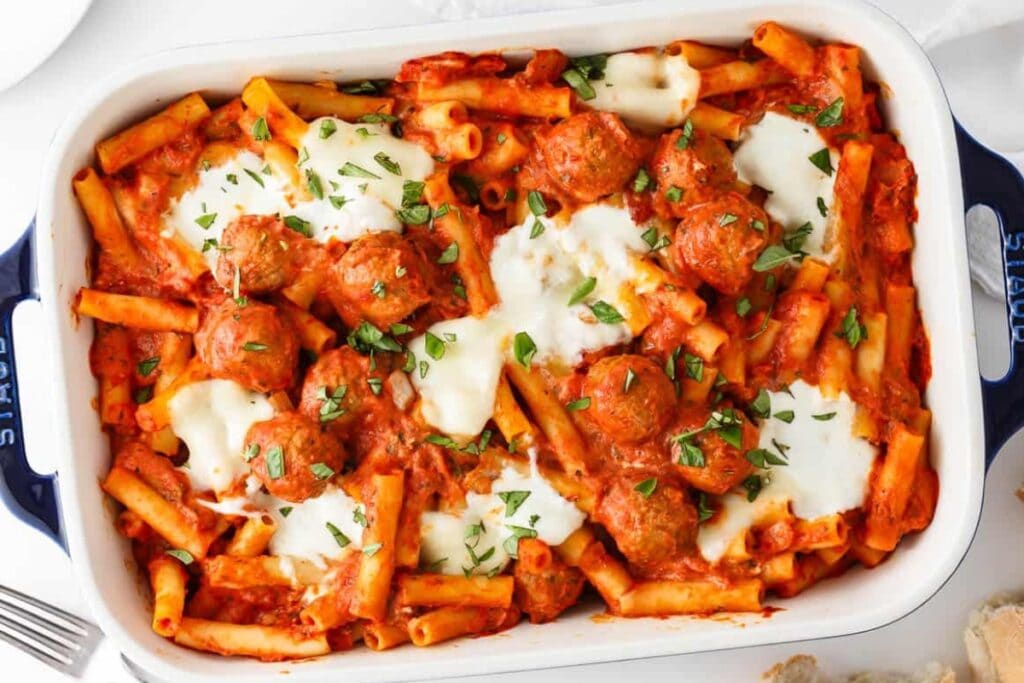 Baked ziti with meatballs in a baking dish.