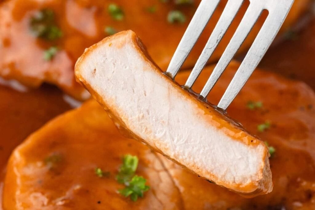 Close up of BBQ pork chop on a fork.