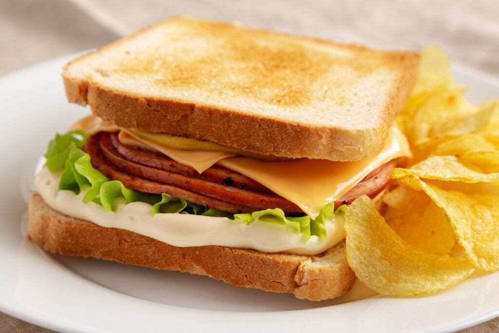 Bologna sandwich with chips on a plate.