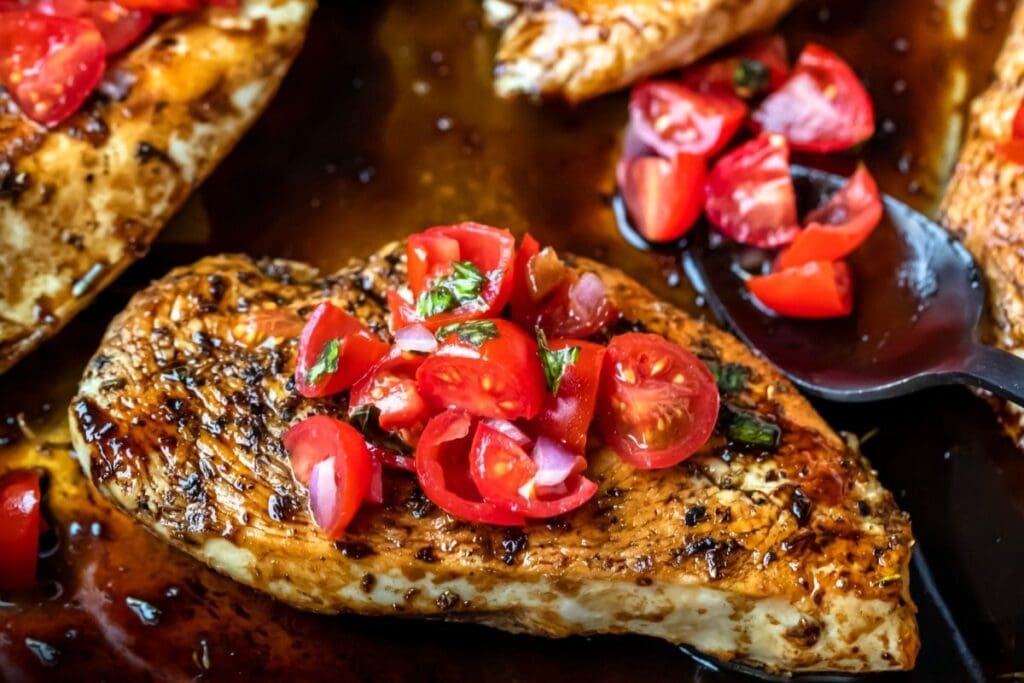 Close-up of bruschetta chicken topped with fresh grape tomatoes and basil.