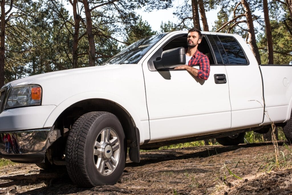 Man sitting in pick up car in forest.