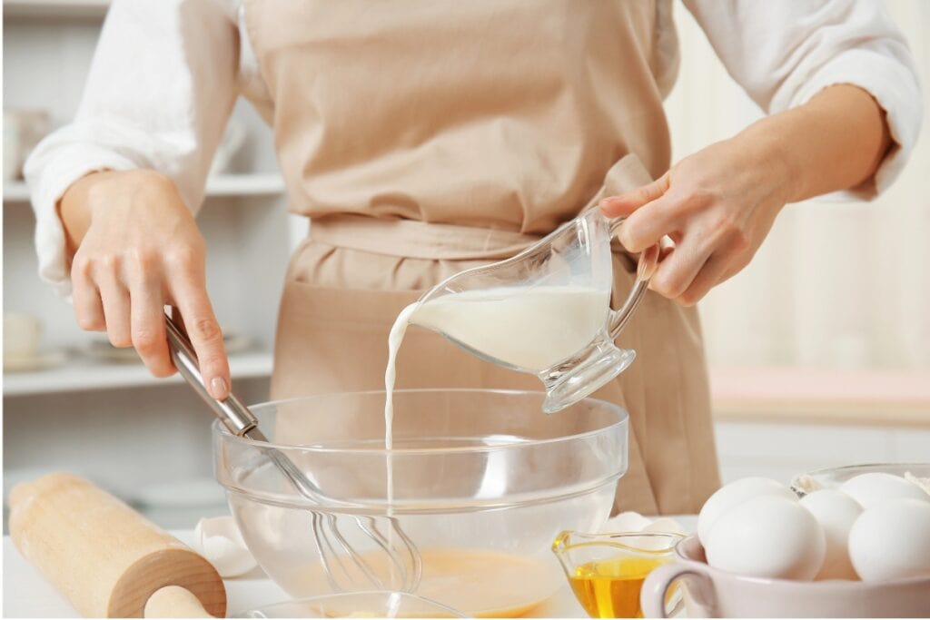 Pouring evaporated milk into a mixing bowl for baking.