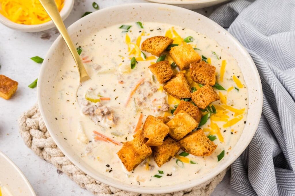 Bowl of cheeseburger soup topped with brioche croutons.