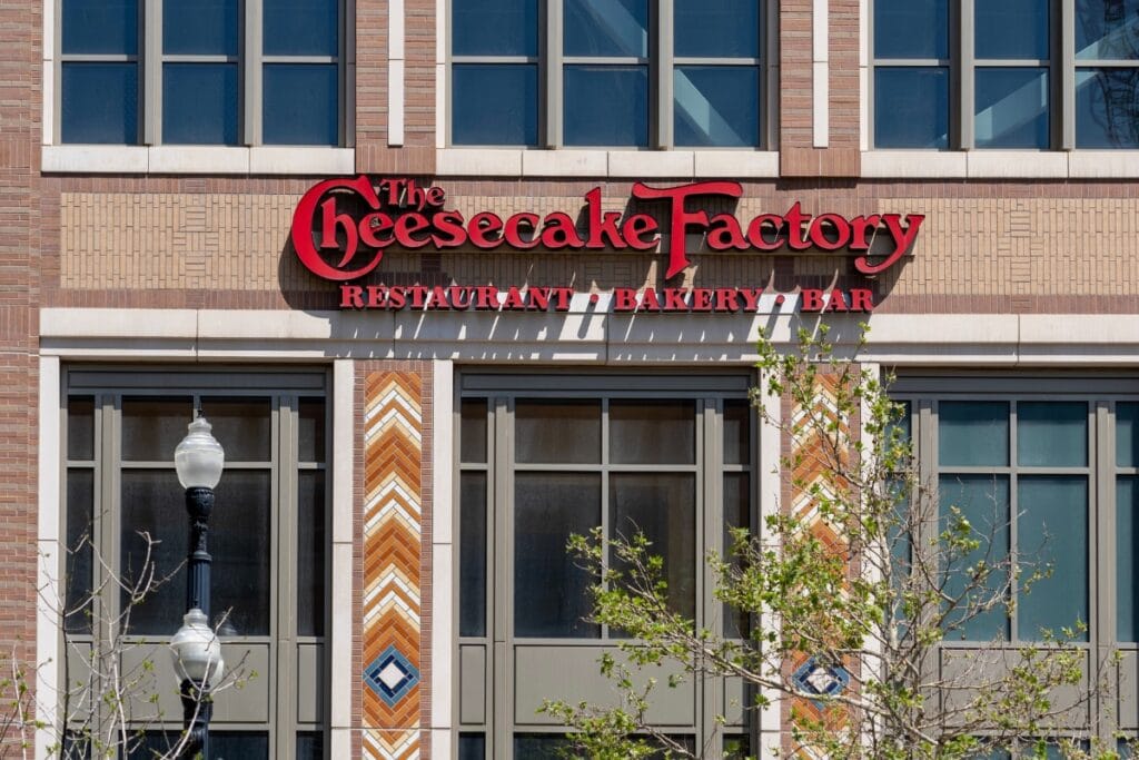 Cheesecake Factory exterior with cream walls and red signage.