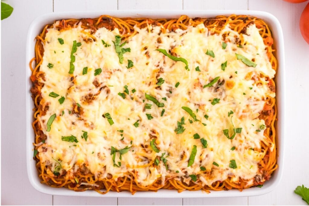 Cheesy baked spaghetti in rectangular baking dish.
