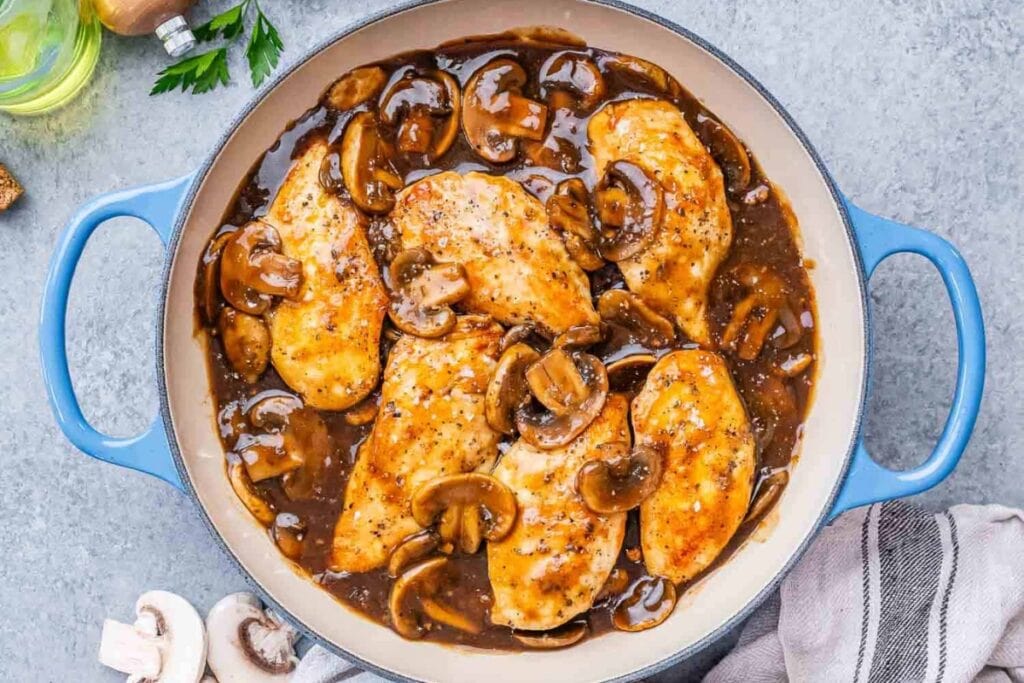 Chicken marsala in a skillet with mushrooms and rich sauce.
