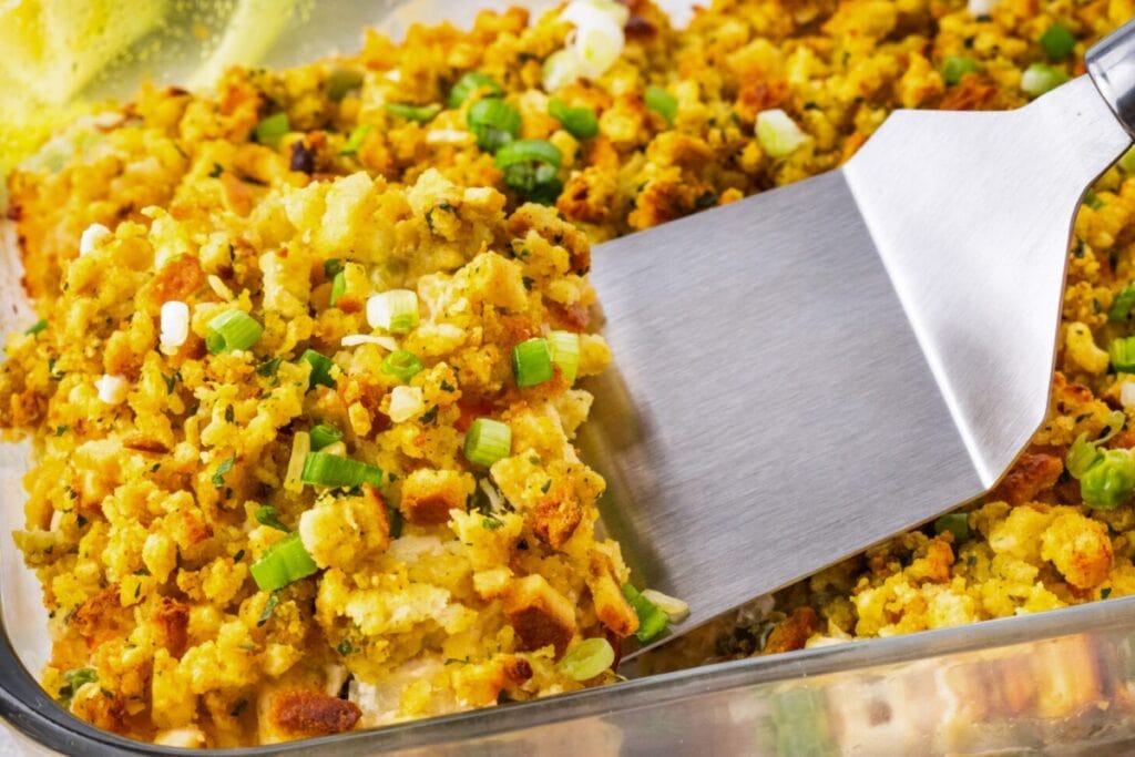 Chicken stuffing casserole in a baking dish with a spatula.