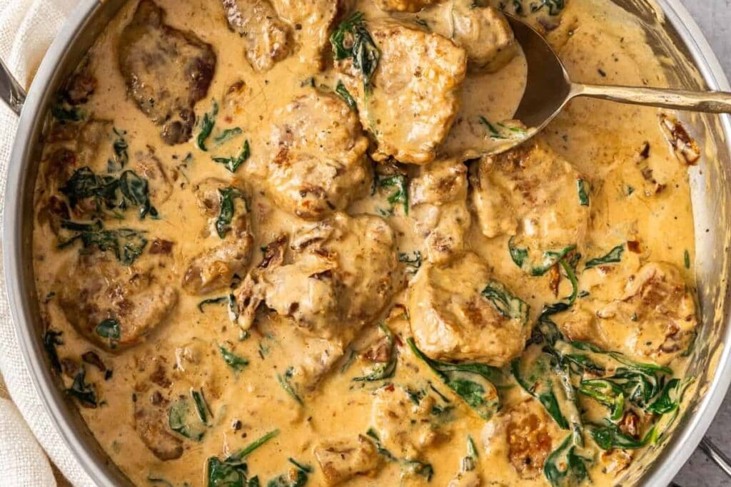 Creamy pork tenderloin medallions in a skillet.