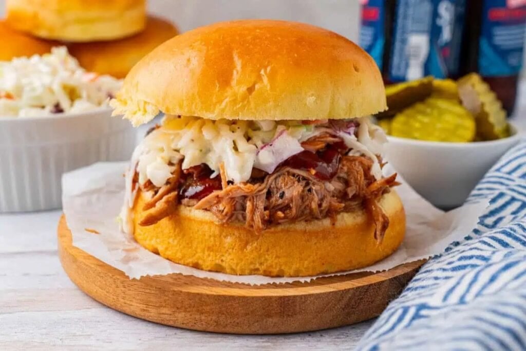 Crockpot BBQ pulled pork sandwich on a wooden board.