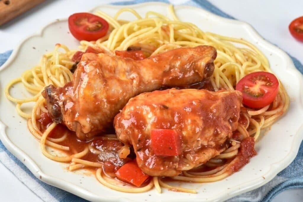 Slow-cooked chicken cacciatore on a plate with pasta.