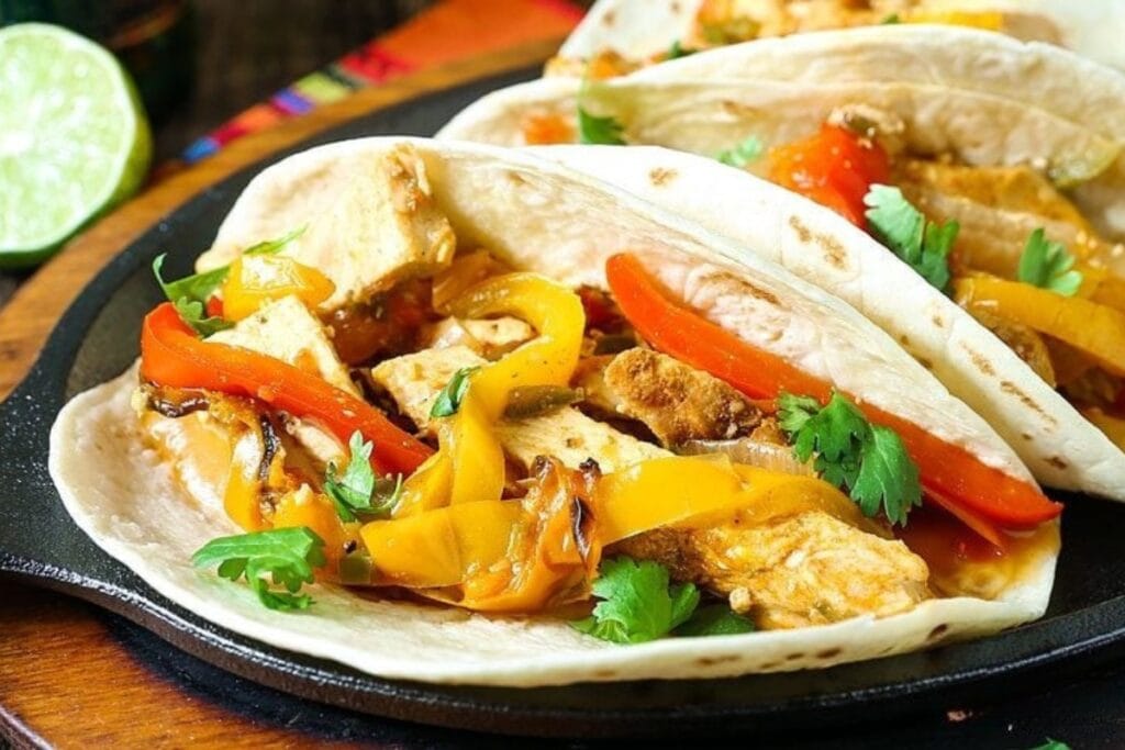 Crockpot chicken fajitas on a flat sizzling plate.