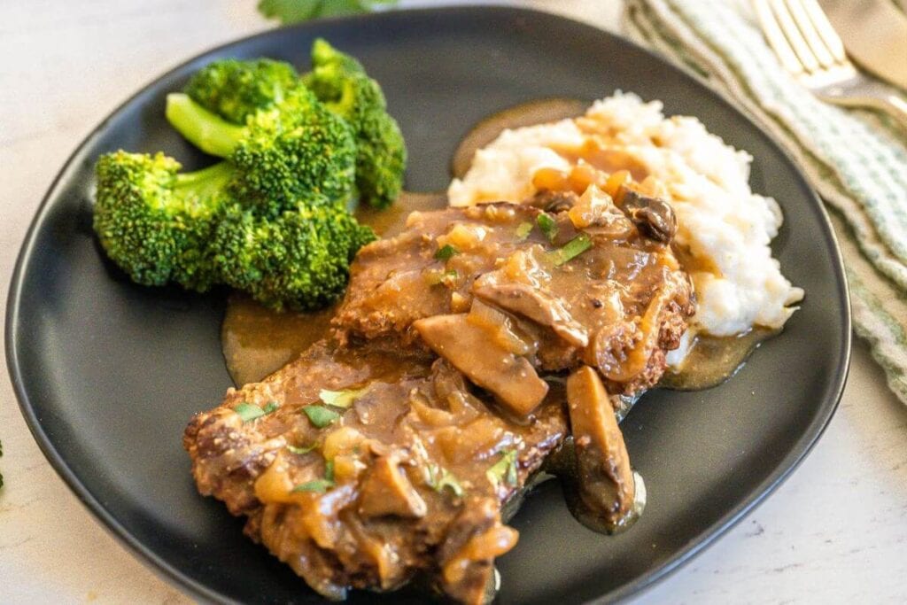 Crockpot cube steak on a plate with broccoli.