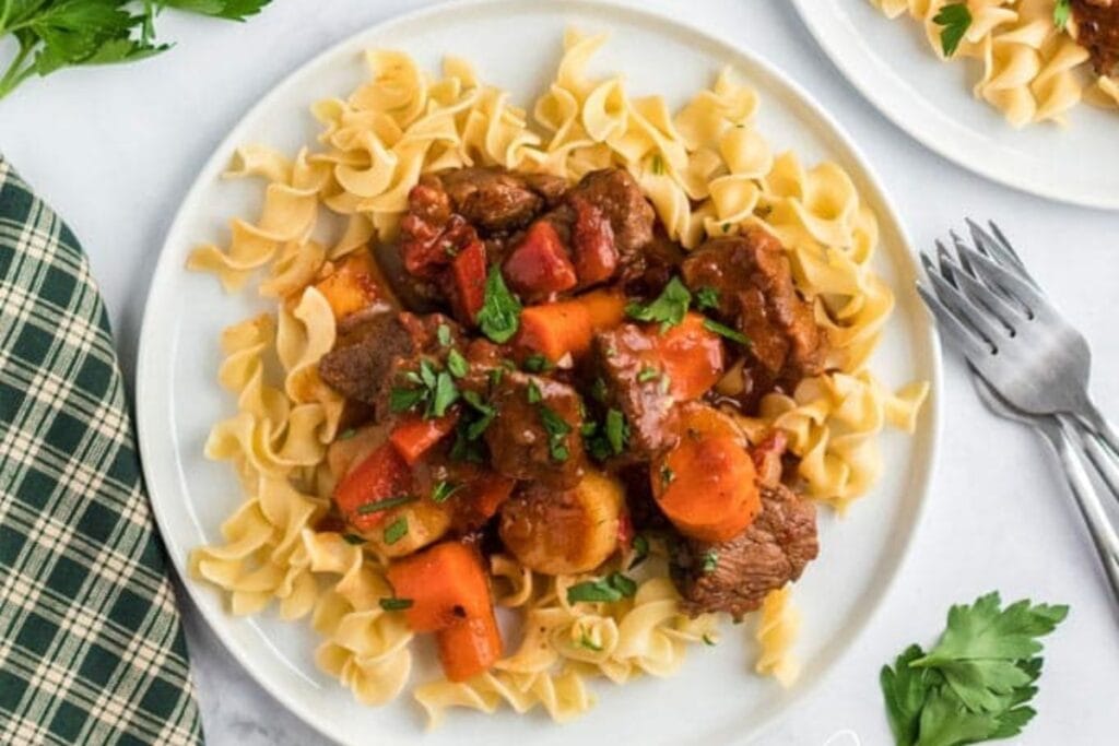 Hungarian goulash served on a plate with noodles.