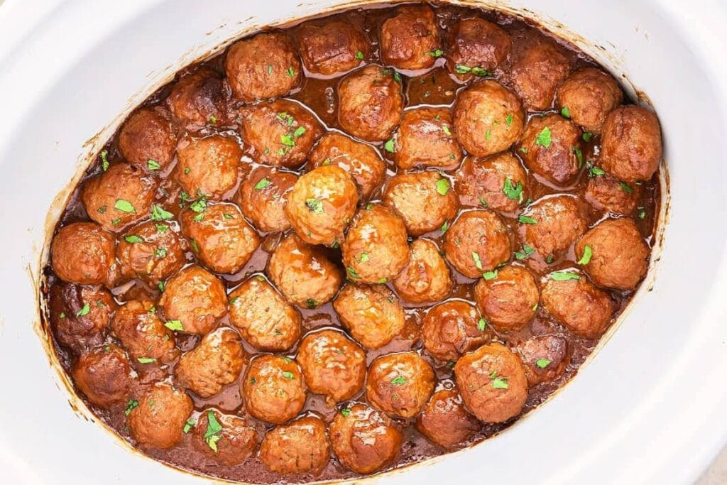 Meatballs simmering in gravy in a crockpot.