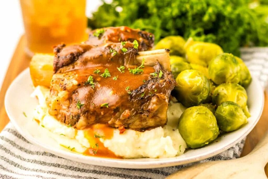 Crockpot short ribs served with mashed potato and mini cabbage on a plate.