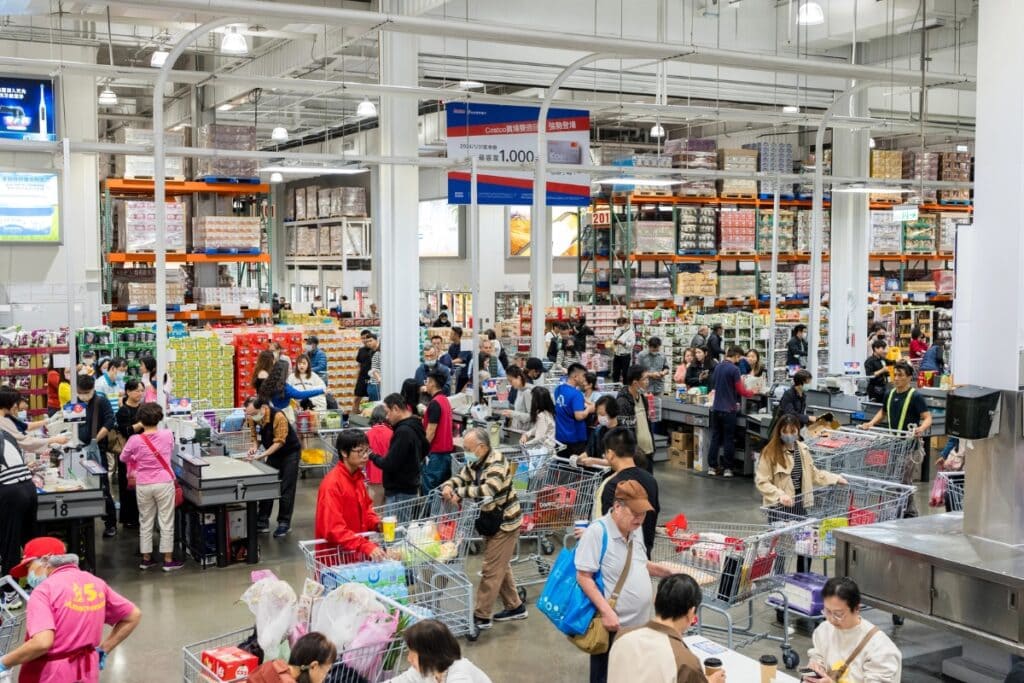 Crowded Costco store with many shoppers and carts at checkout.