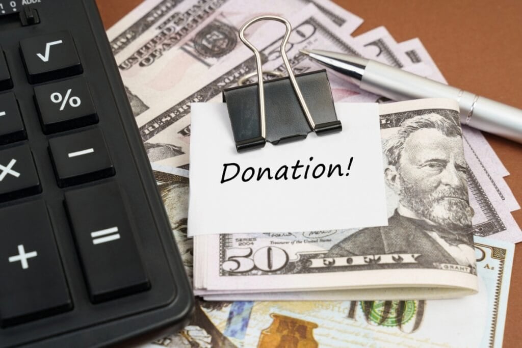 Dollar bills with a note saying "Donation!" clipped beside a calculator and pen.