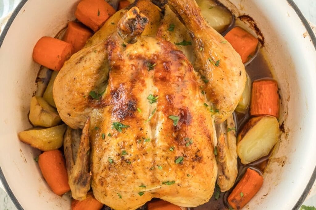 Whole chicken with potatoes and carrots in a Dutch oven.