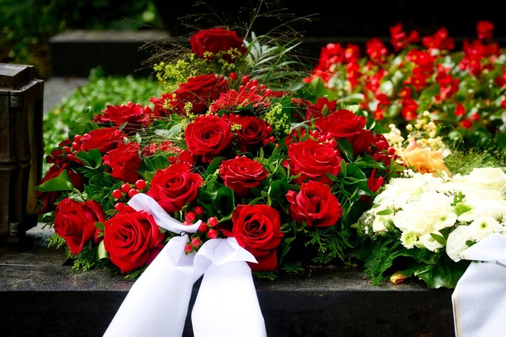 Red roses with a white funeral ribbon.