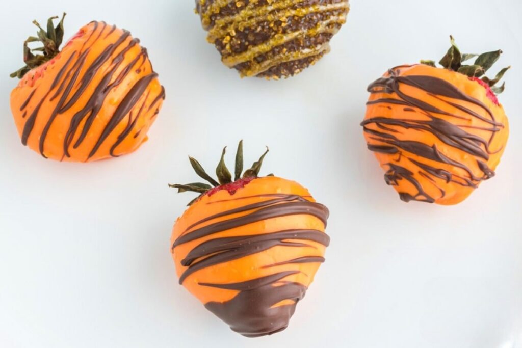 Fall chocolate covered strawberries on a white plate.