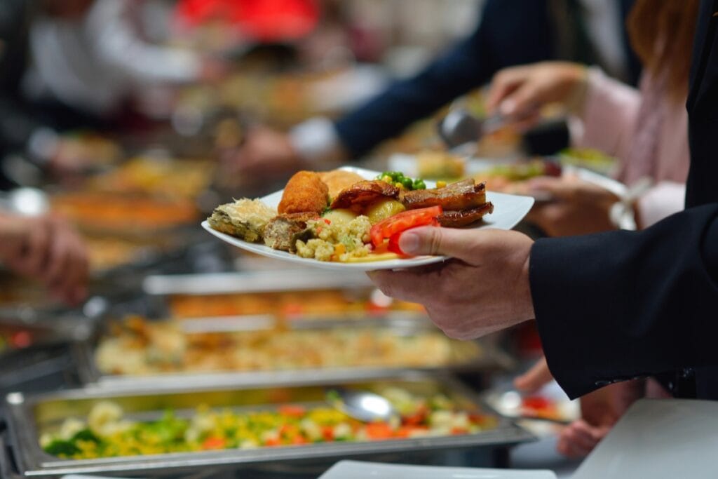 Man holding a plate full of food at a buffet.