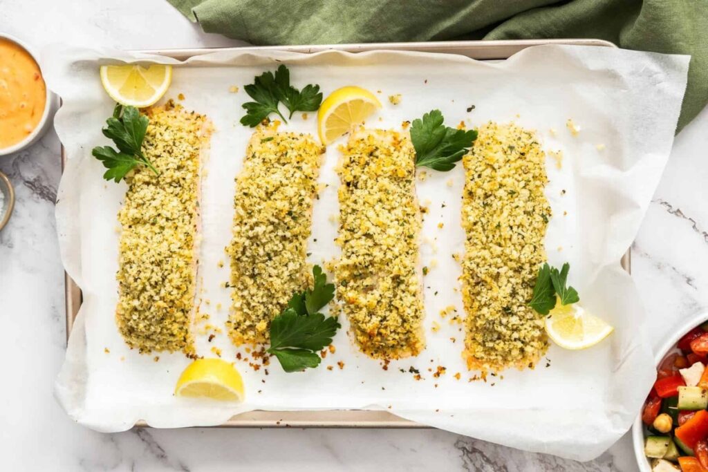 Herb and panko crusted salmon in a sheet pan with parchment paper.