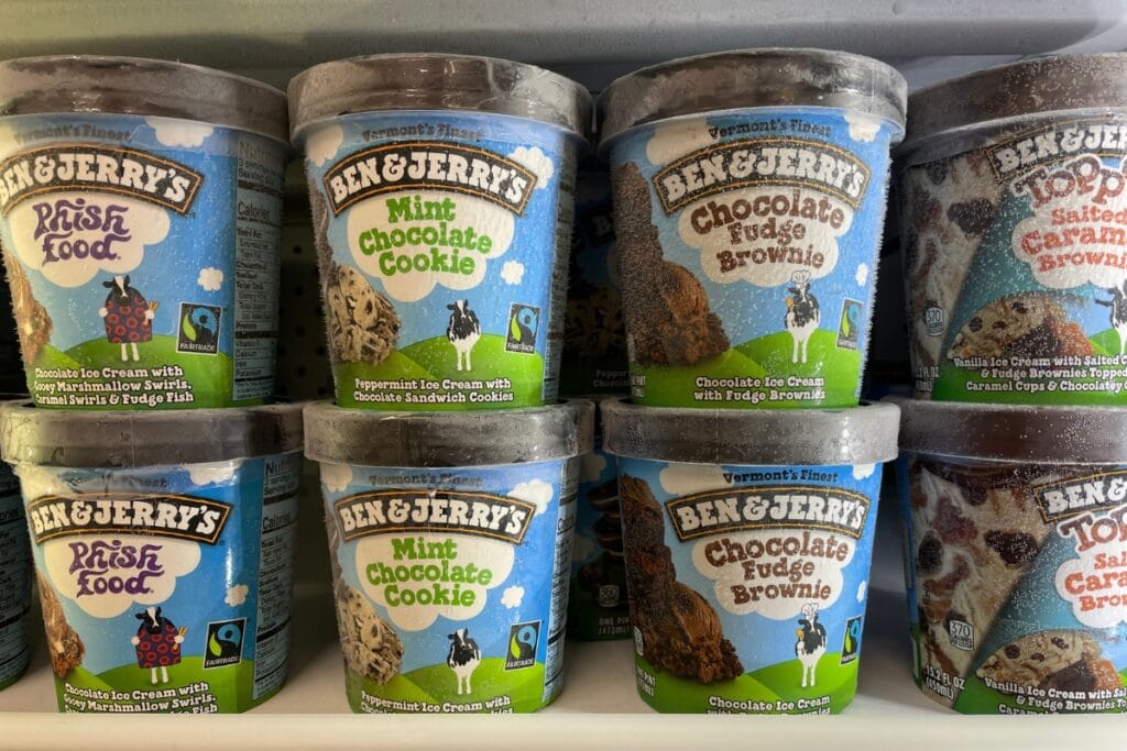 Assorted Ben & Jerry’s ice cream pints displayed on a grocery store freezer shelf.