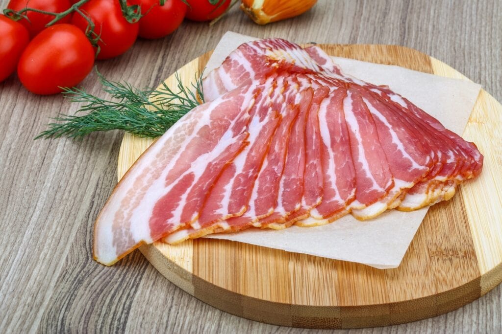 Slices of bacon arranged on a round wooden board.