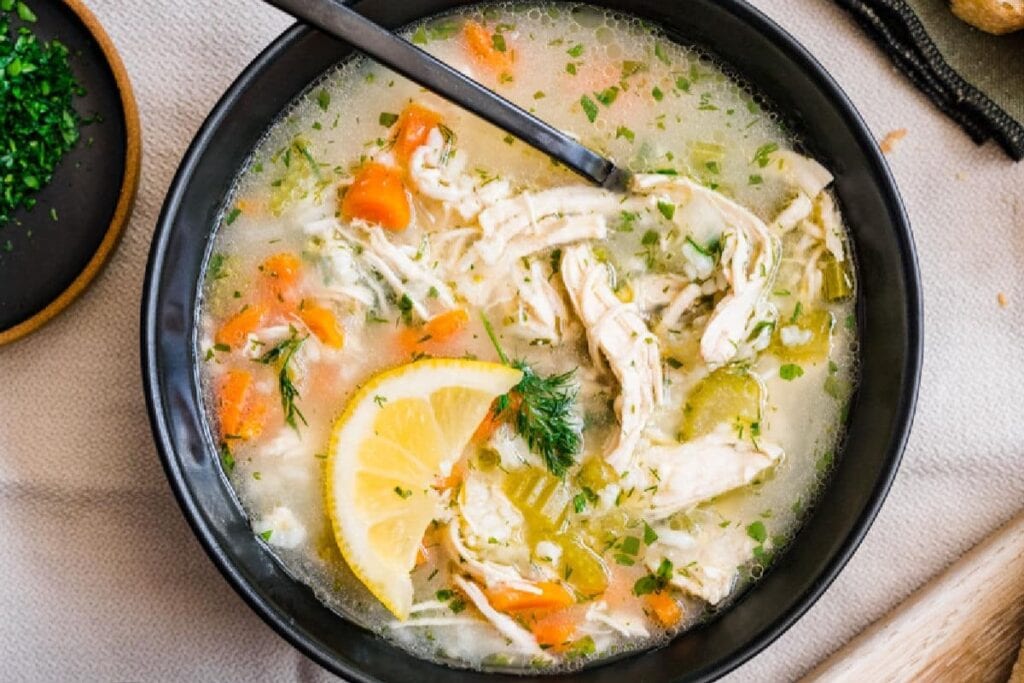 Lemon chicken rice soup in a black bowl.
