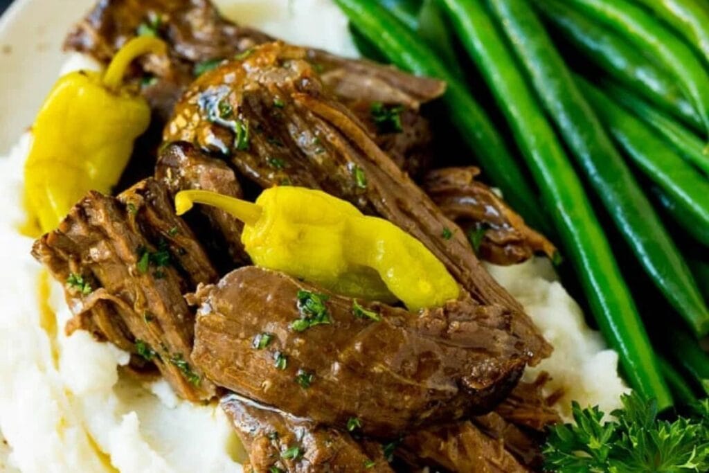 Mississippi pot roast on a plate with mashed potatoes and green beans.