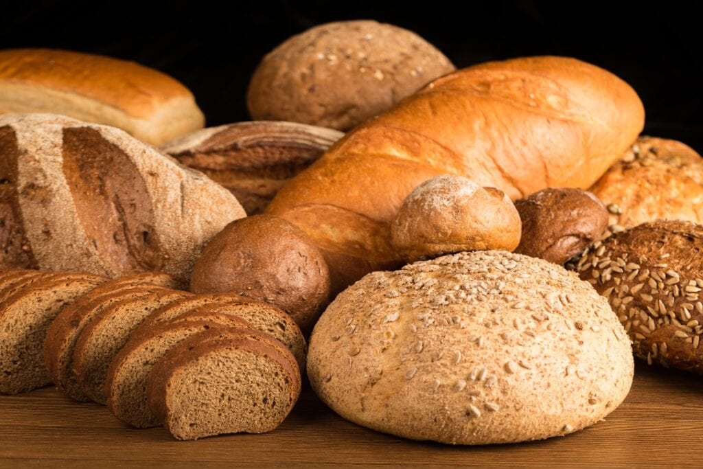 Assorted loaves and rolls of bread on a wooden table.