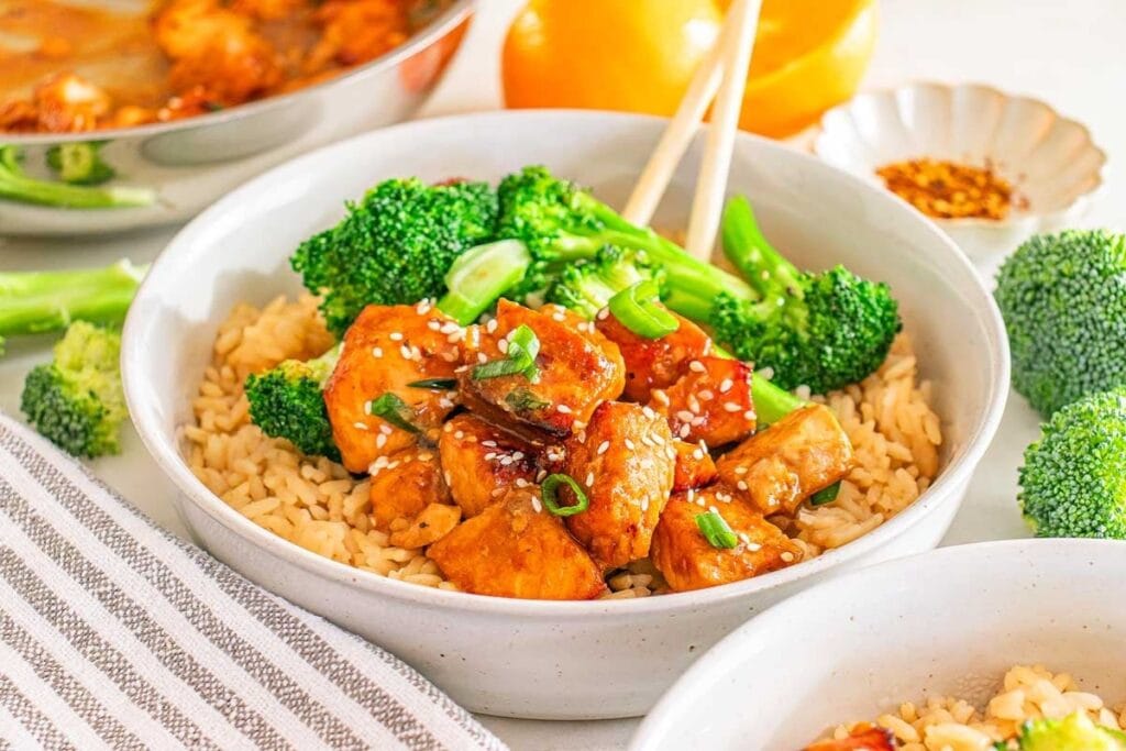 Orange salmon bites in a bowl with broccoli and rice.