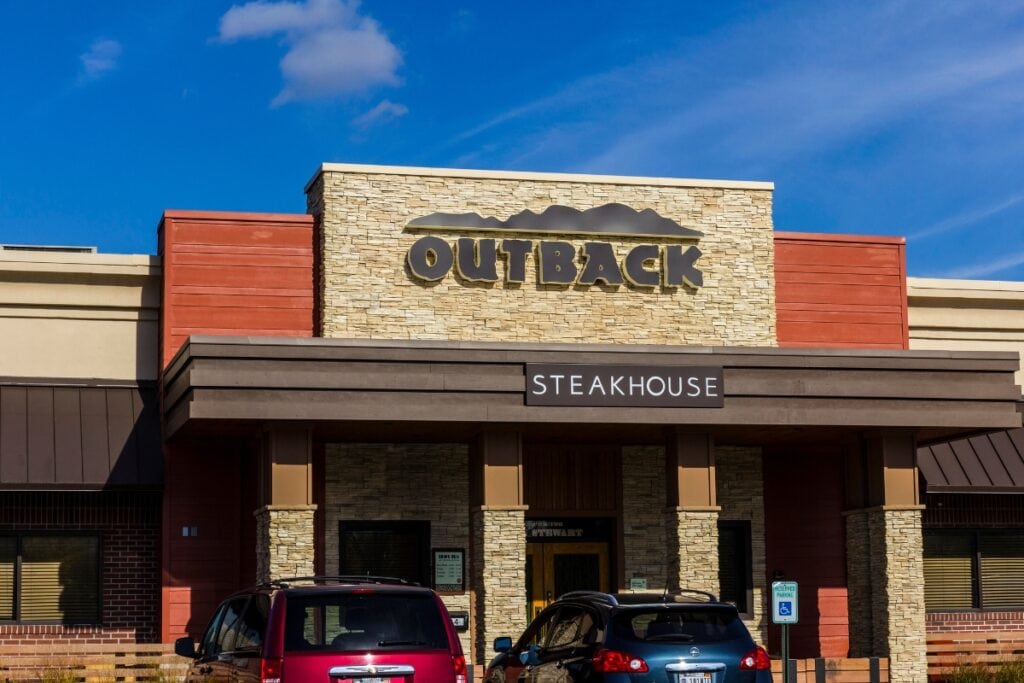 Outback Steakhouse restaurant exterior with cars parked in front.