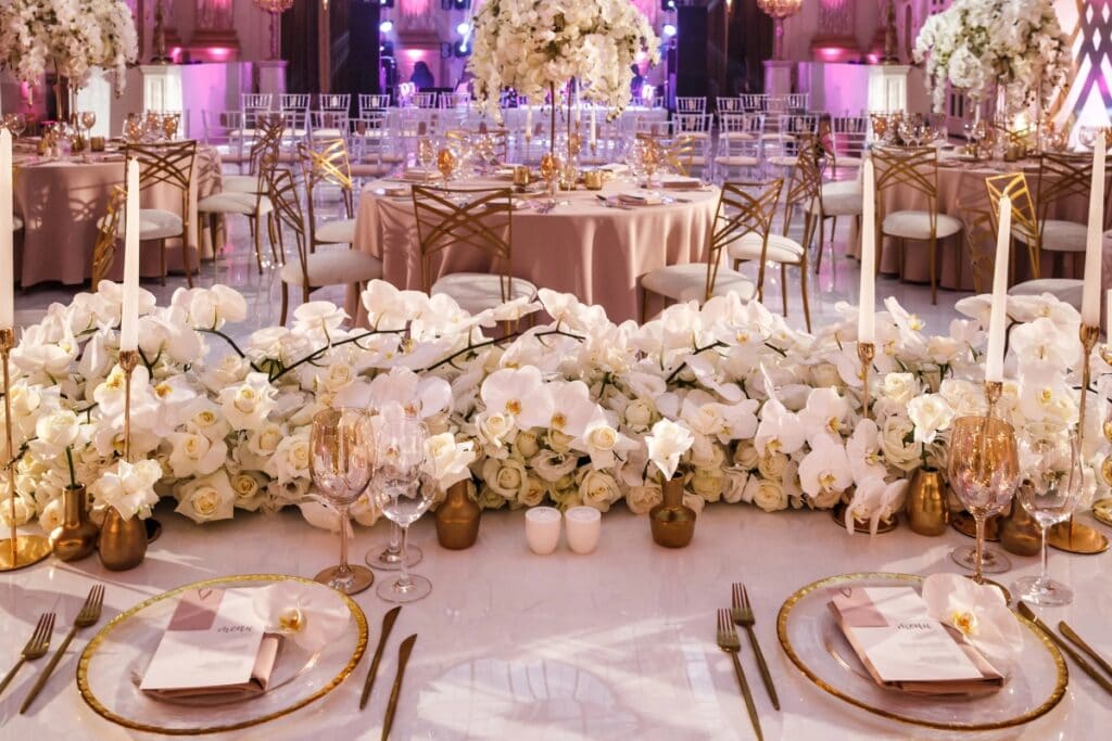 Elegant wedding table with gold accents, white floral arrangements, and candles.
