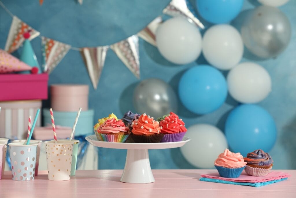 Colorful party supplies including balloons, cups, cupcake stand, and decorations.