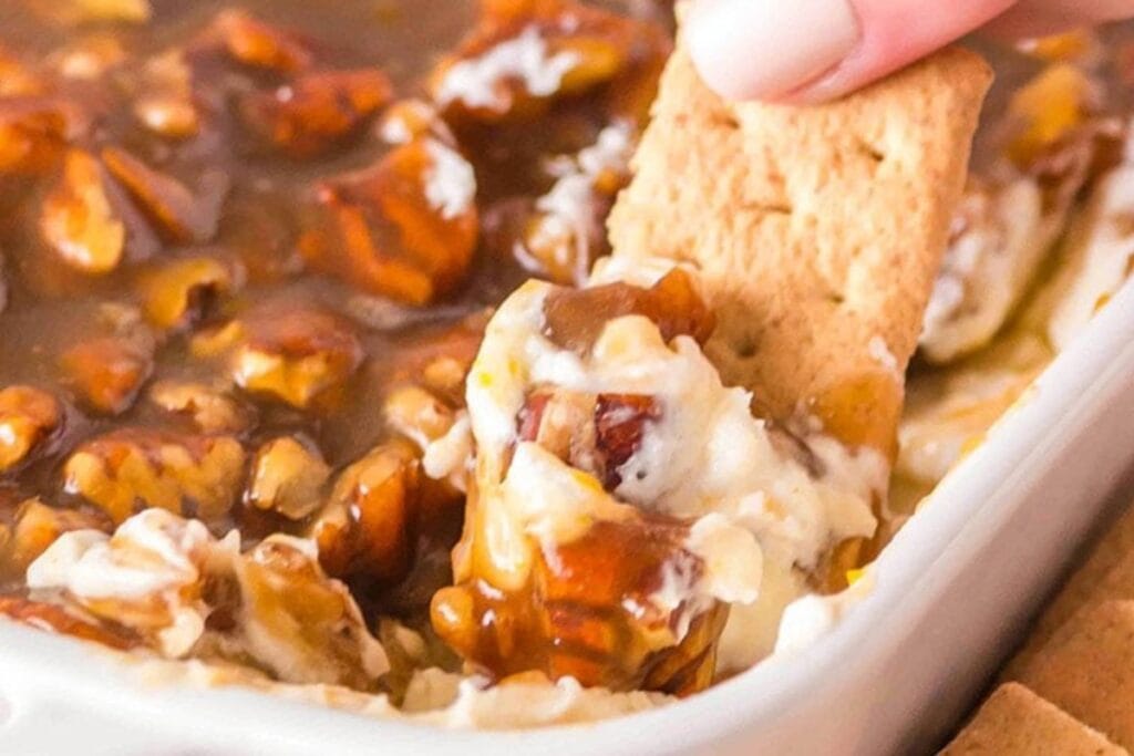 Close-up of pecan pie dip with a cracker being dipped.