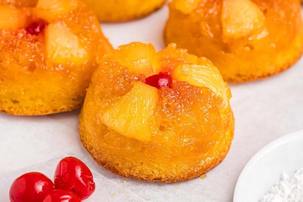 Mini pineapple upside down cupcakes on parchment paper.