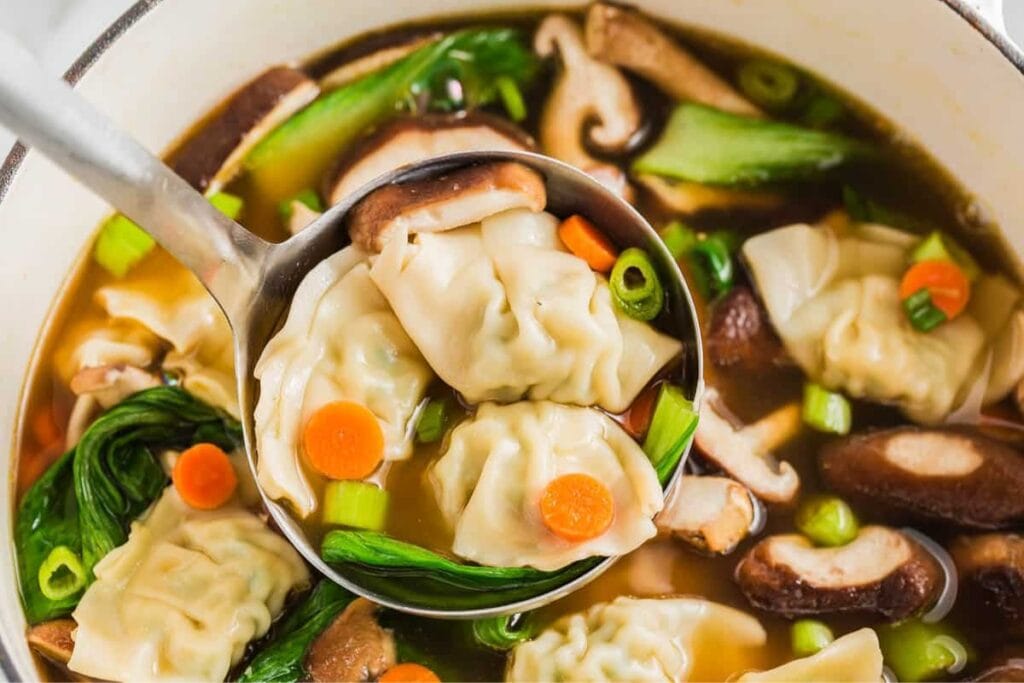 Potsticker soup with dumplings in a ladle.