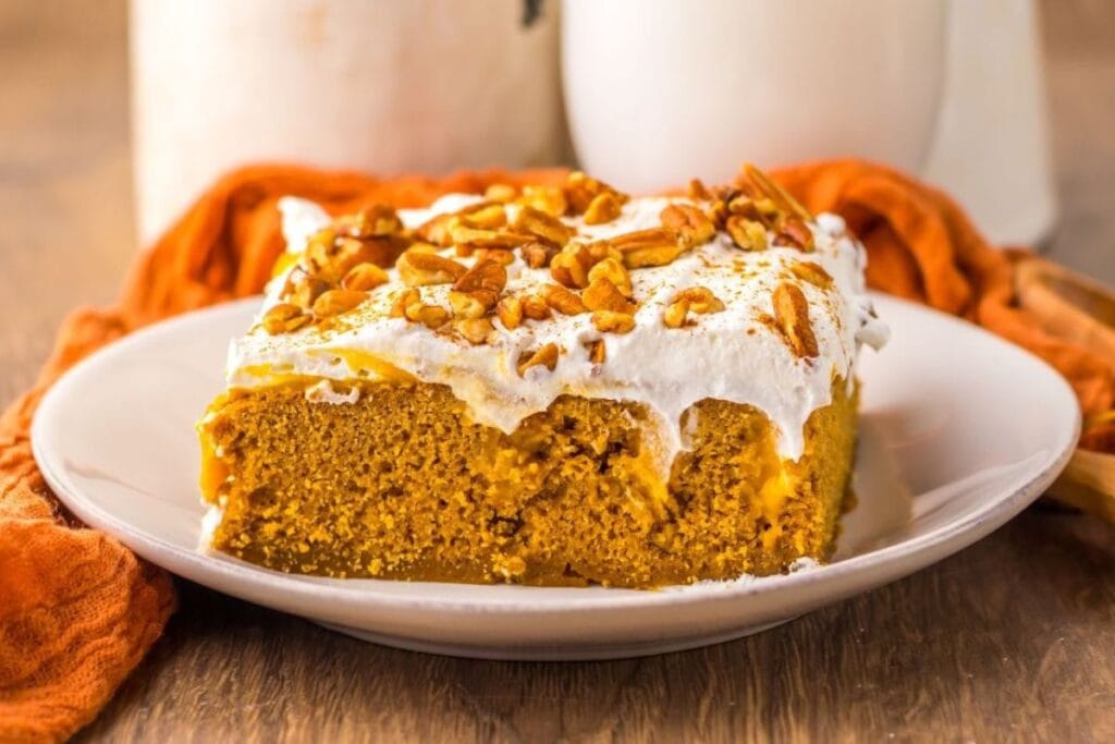 Pumpkin poke cake with orange towel in background.