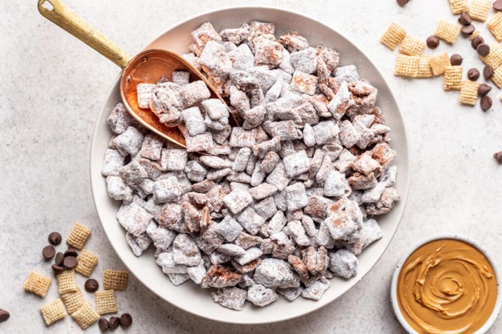 Powdered sugar-coated puppy chow snack mix in a bowl.