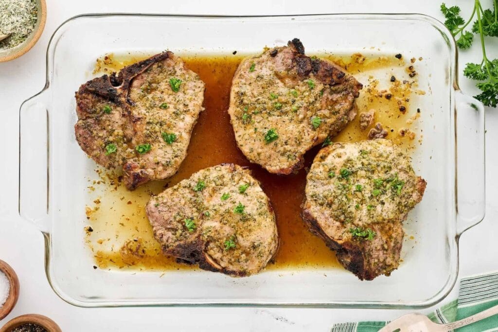 Ranch oven-baked pork chops in a glass baking dish.