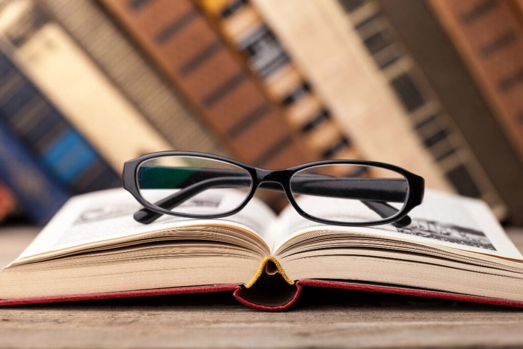 Reading glasses placed on an open book inside a library.