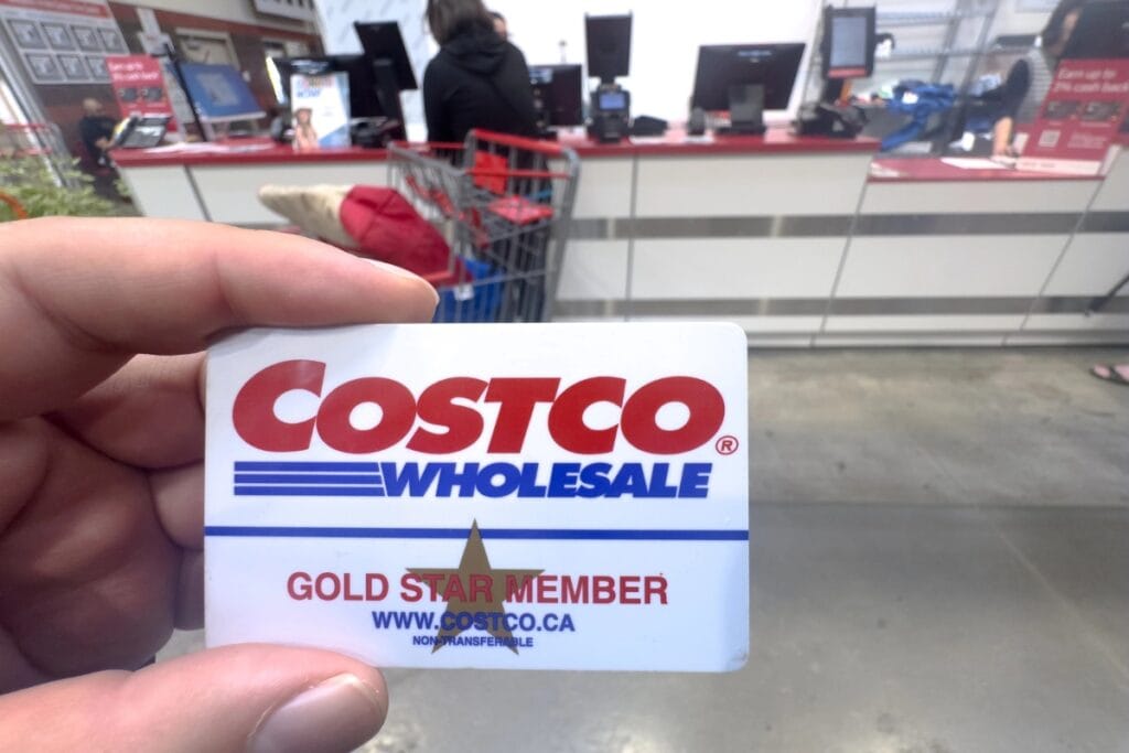 Hand holding Costco membership card at checkout counter.