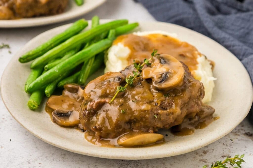 Salisbury steak served with green beans on a plate.