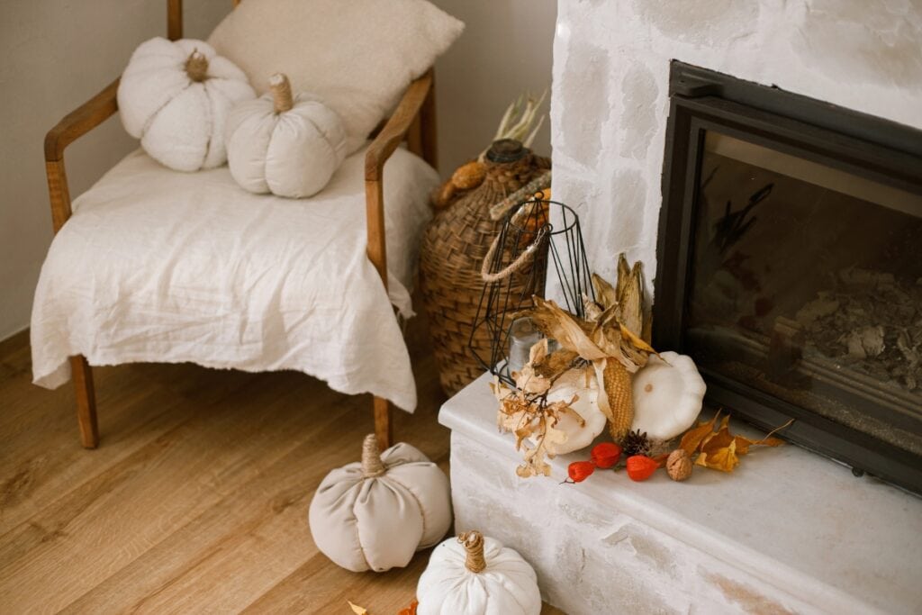 Autumn seasonal decorations with pumpkins pillows, leaves, and candles.