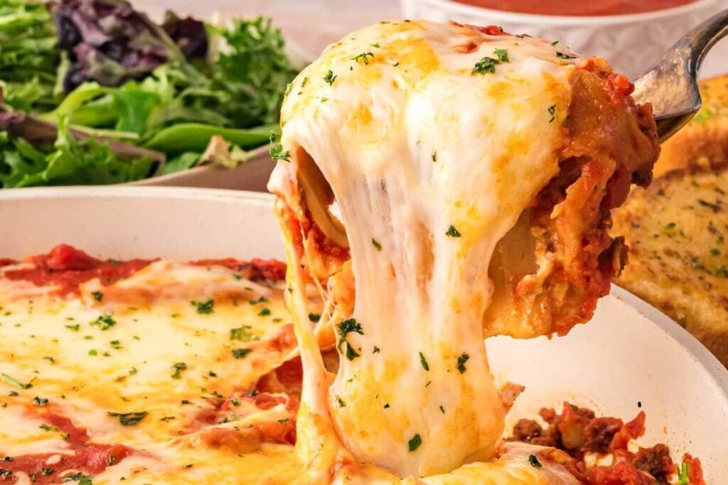 Close up of skillet lasagna on a spoon with gooey melted cheese.